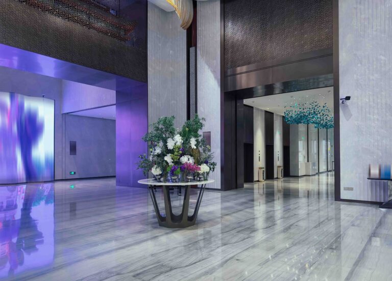 Luxurious hotel lobby with a sophisticated design. The lobby features a grand entrance with high ceilings and a polished marble floor that reflects the ambient lighting.