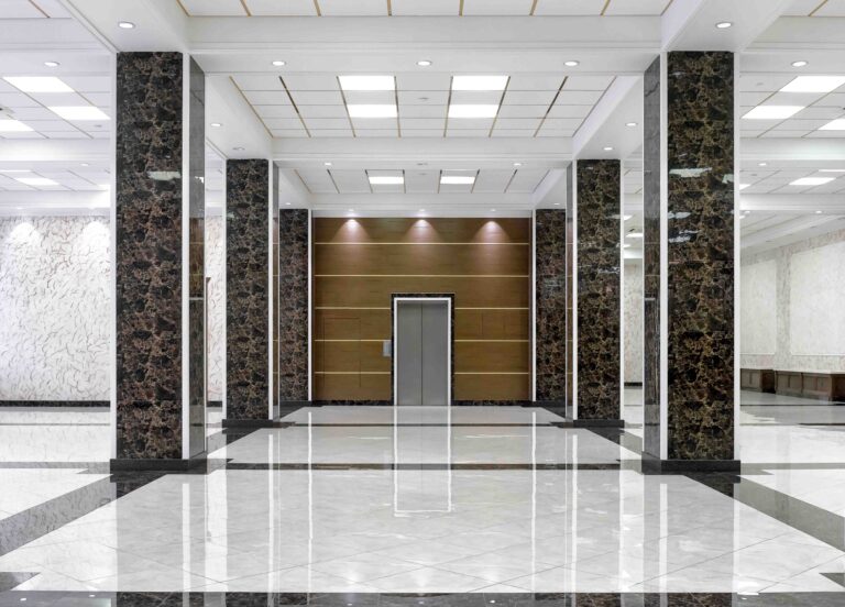 Luxurious hotel lobby with a sophisticated design. The lobby features a grand entrance with high ceilings and a polished marble floor that reflects the ambient lighting.