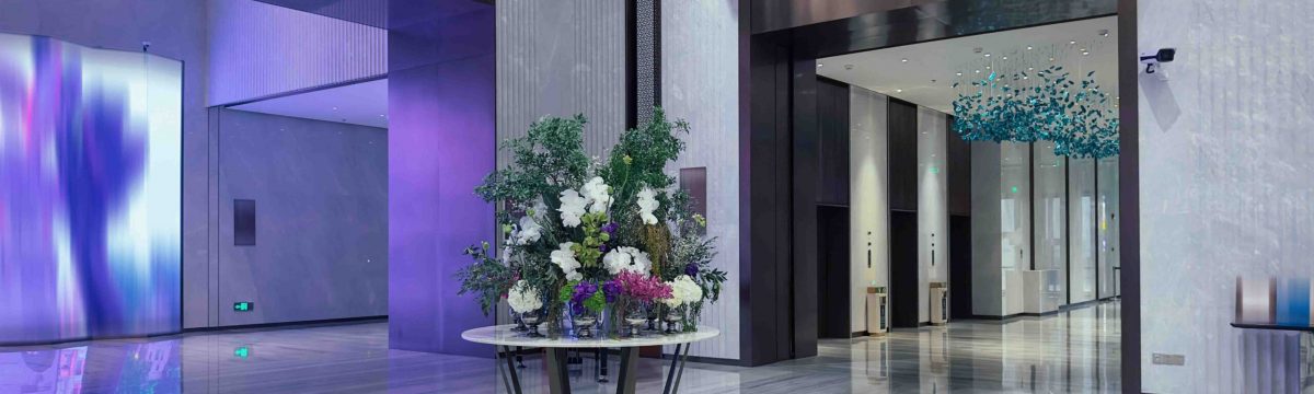 Luxurious hotel lobby with a sophisticated design. The lobby features a grand entrance with high ceilings and a polished marble floor that reflects the ambient lighting.
