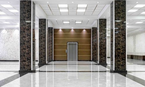 Luxurious hotel lobby with a sophisticated design. The lobby features a grand entrance with high ceilings and a polished marble floor that reflects the ambient lighting.